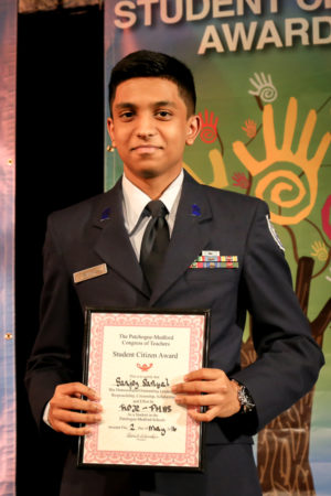 A Boy in Uniform Holding an Award on Stage